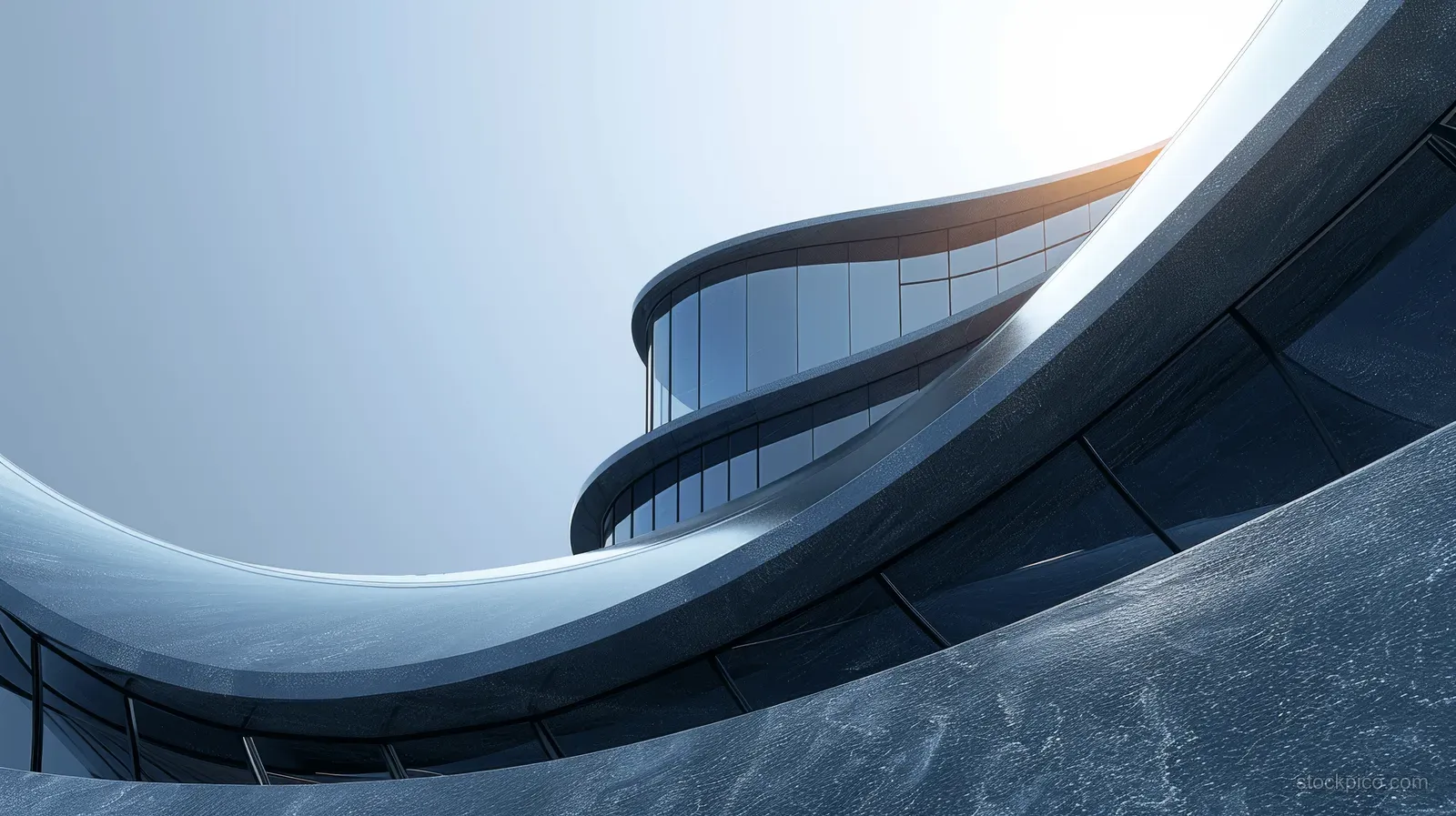 Curved futuristic building facade rises over an empty asphalt roadway beneath a clear blue sky.