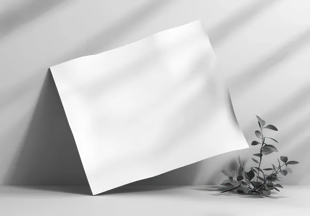 Blank white paper mockup sheet angled on light gray surface with soft shadows
