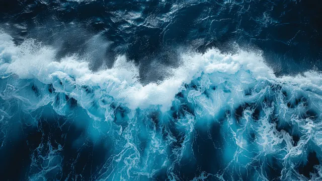 Aerial ocean waves with white foam rolling in turquoise blue water from above