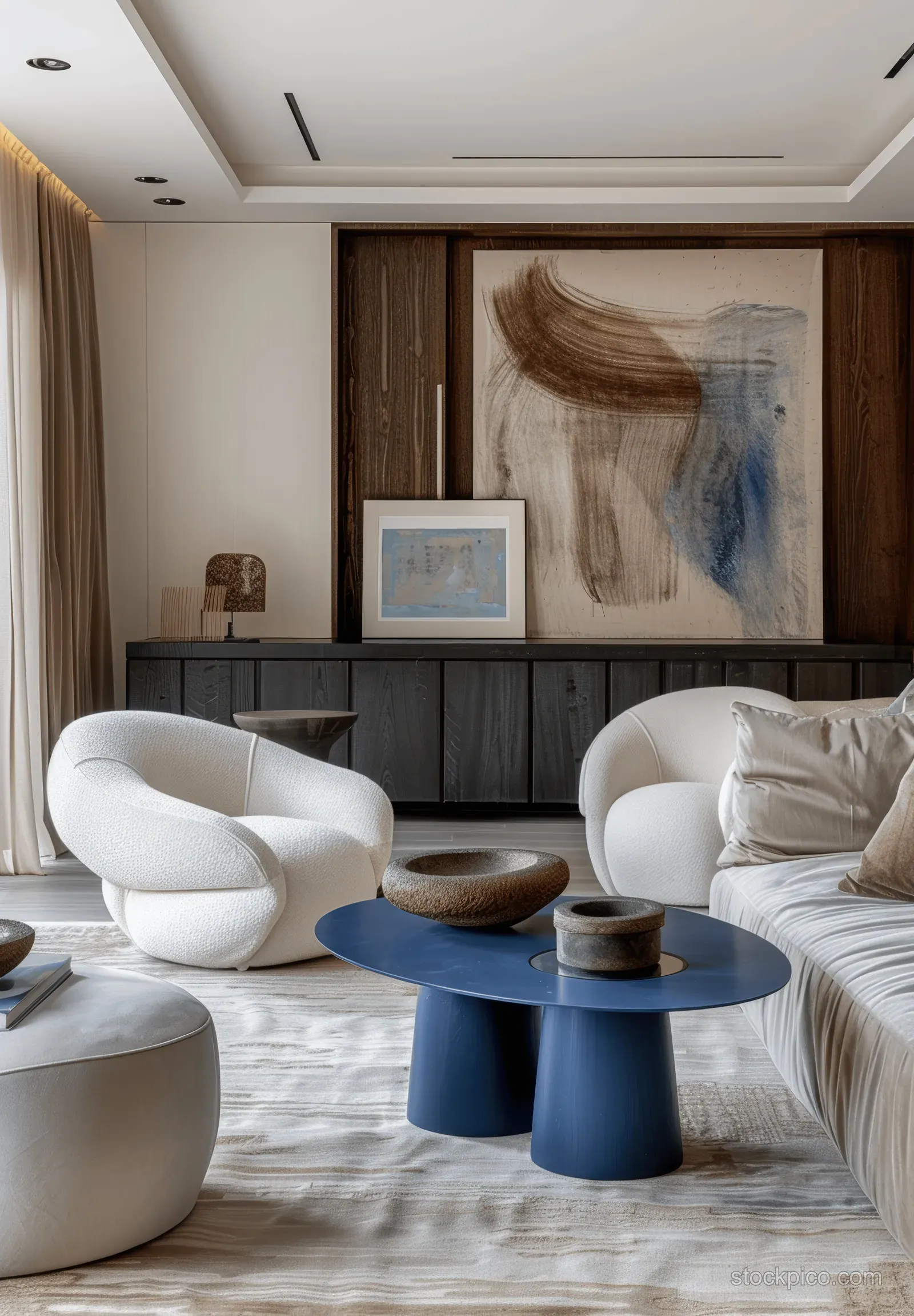 Minimalist living room with a blue oval coffee table, white chairs, beige rug, and abstract wall artwork.