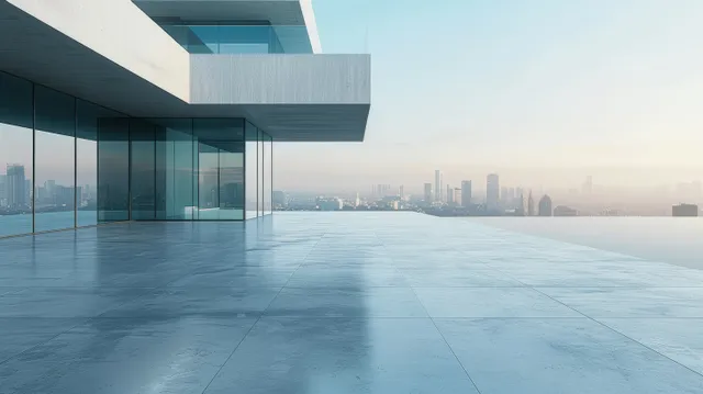Empty minimalist concrete terrace with glass building frontage overlooking a distant city skyline at sunrise.