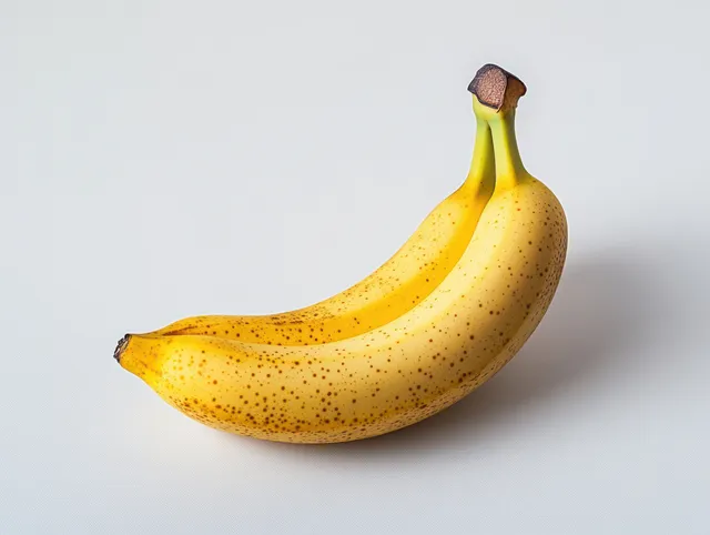 Two ripe yellow bananas with brown spots rest on a clean white background, showcasing their fresh texture and sweetness.