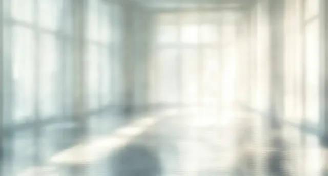 Sunlight streams through large windows into an empty room, reflecting on the smooth floor.