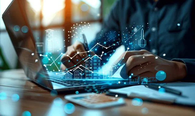 A broker’s hands use a laptop with glowing house icons and market graphs hovering over paperwork.