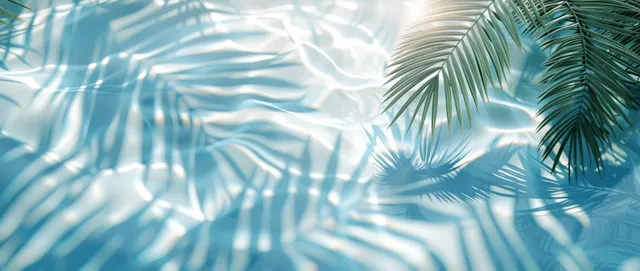 Palm leaf shadows dance across sunlit water surface, light blue abstract summer top view
