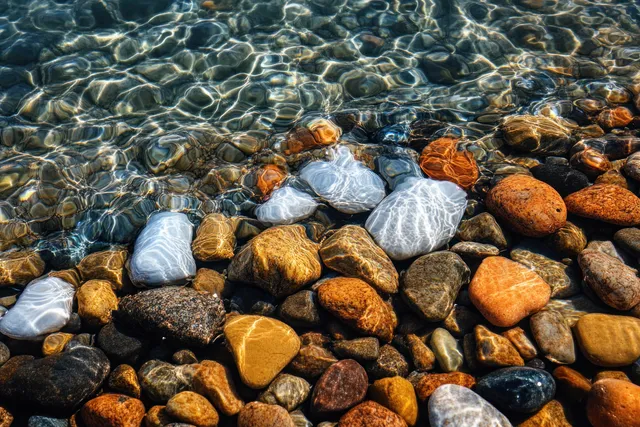 Colorful pebbles beneath rippling clear water along the beach