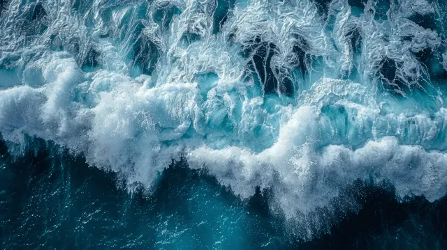 Aerial top-down view of turquoise ocean waves with bright white foam patterns