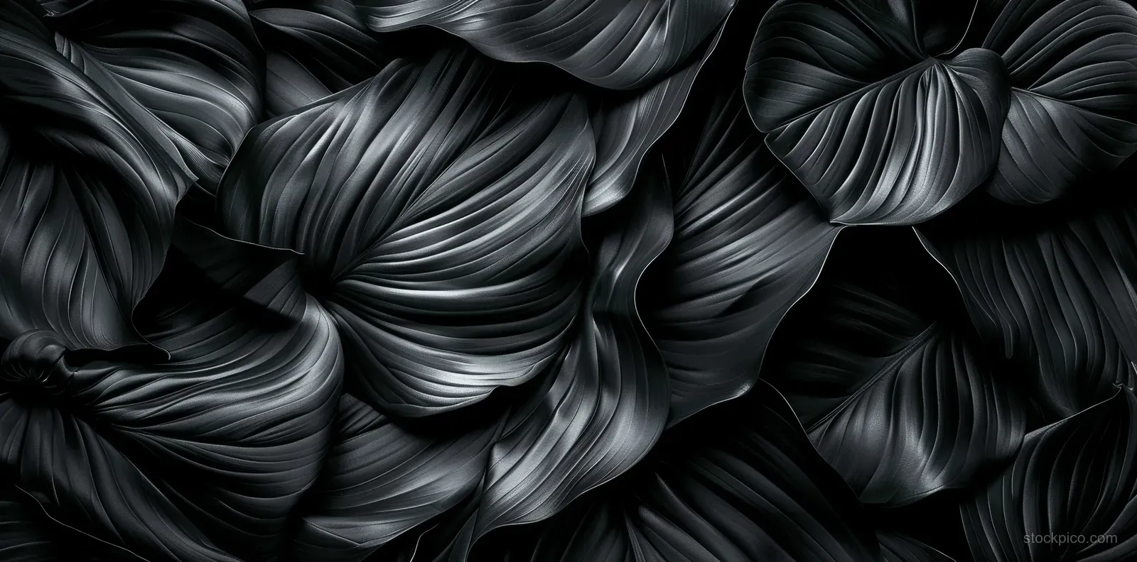 Top view of black satin leaf texture showing swirling crumpled folds and deep shadows across the background.