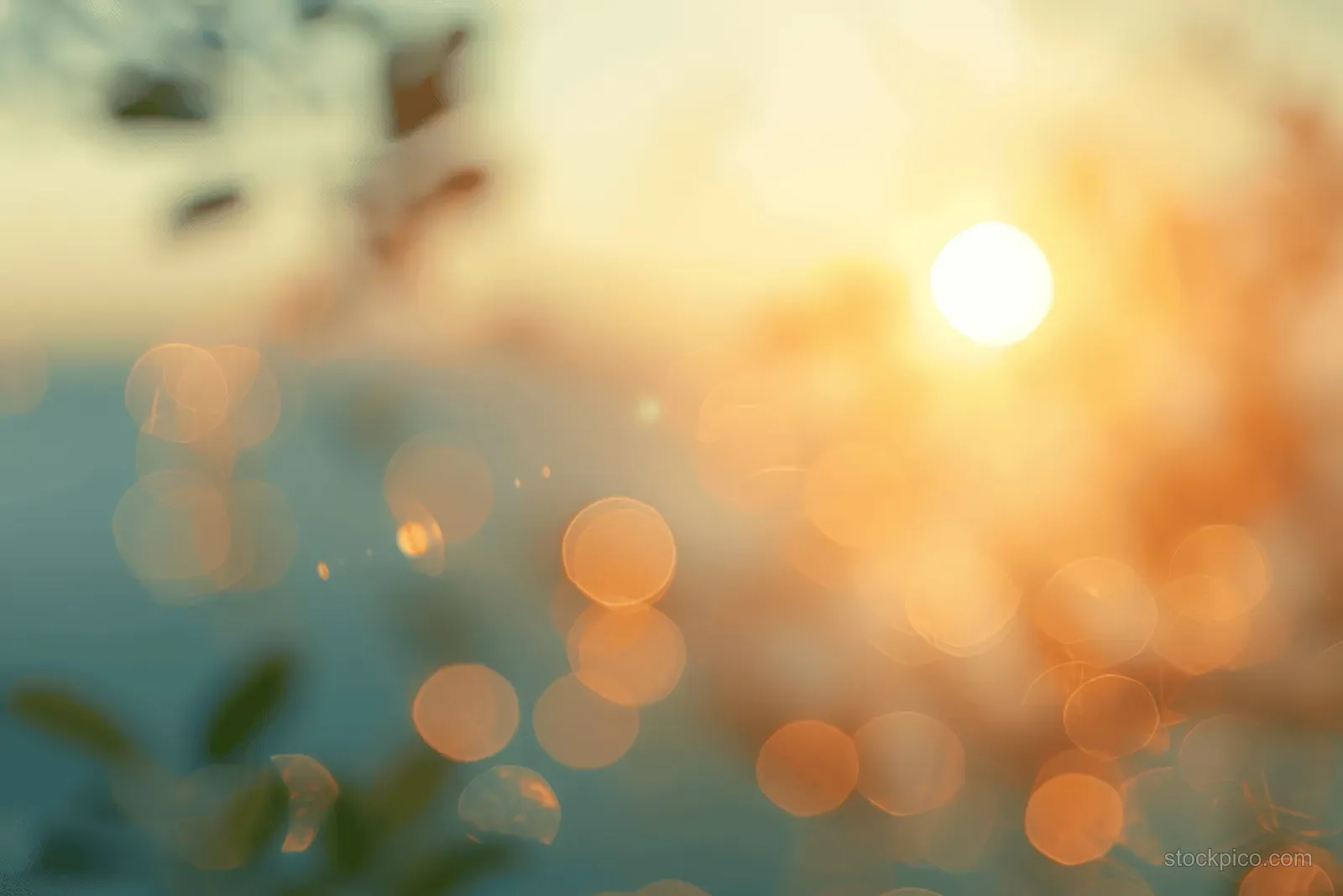 Blurred sunlit sky with warm pastel tones and glowing bokeh light circles over a distant landscape.