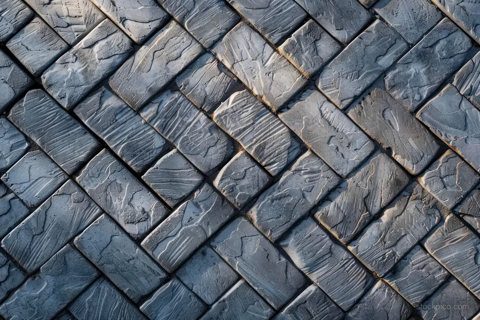 Blue-gray rectangular bricks form a diagonal herringbone pattern with visible grooves and shadows.