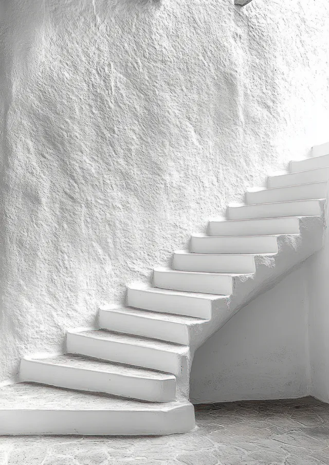 White curved staircase ascends along a textured wall with stone floor and soft daylight shadows.