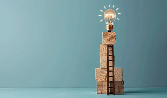 Glowing lightbulb balanced on a wooden ladder stack with small blocks beneath against a light blue background.