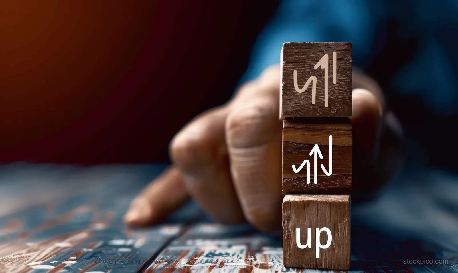 Stacked wooden blocks with upward arrows sit on a desk next to a printed chart, symbolizing rising rates.