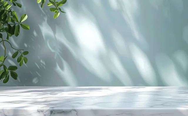 White marble table with dappled leaf shadows against a soft blue blurred wall