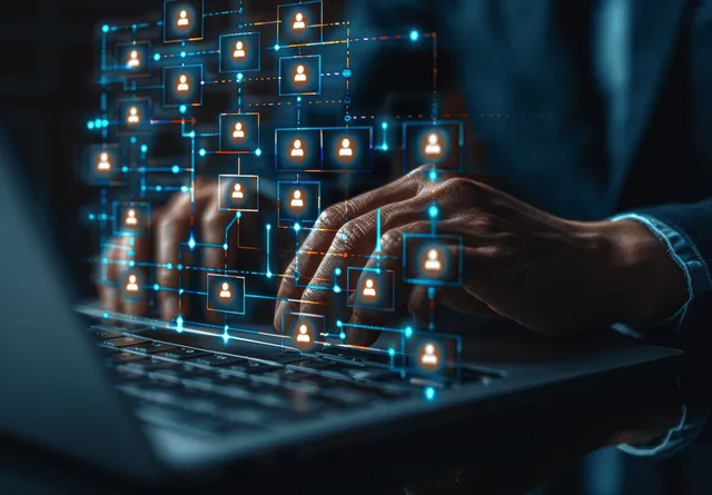 Businessman typing on a laptop with a glowing organization chart overlay above the keyboard.
