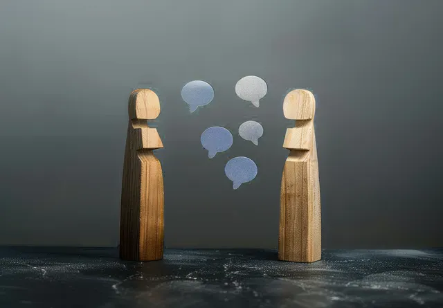 Two wooden human figures face each other with blue speech bubbles between them