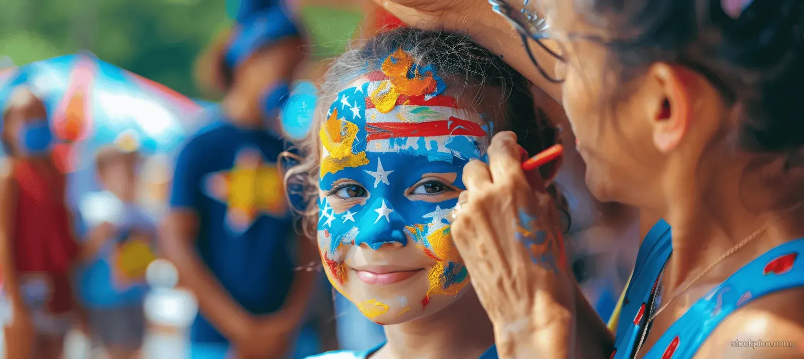 An artist paints a colorful patriotic star face design on a child at a family celebration.