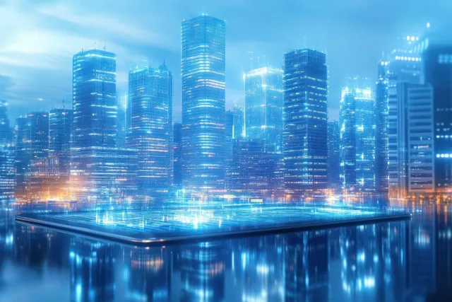 Glowing blue futuristic skyscrapers at night reflect in water while a lit digital tablet surface fills the foreground.