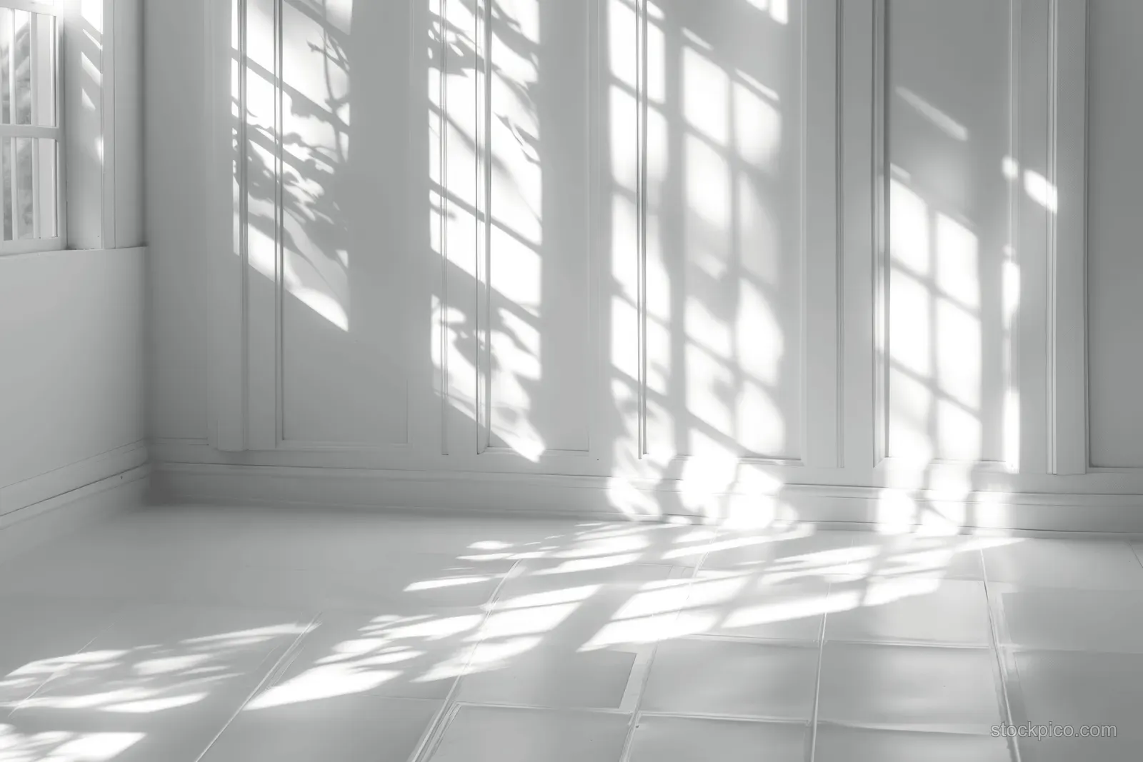 Sunlight grid through a window casts long shadows over a white tiled floor and wall in a minimalist room.