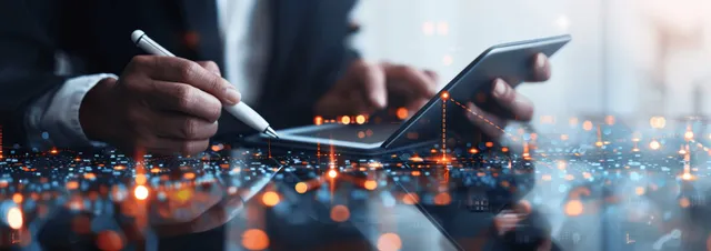 Businessman reviewing HR and CRM dashboards on a digital tablet at networked desk