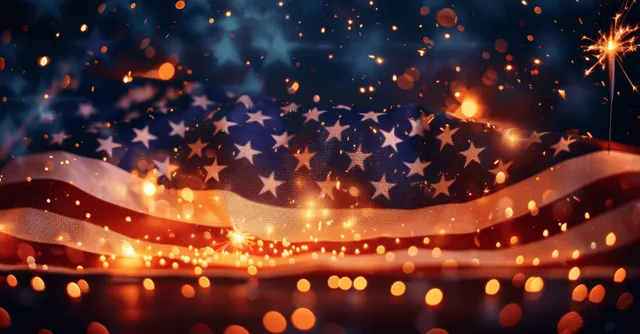 Sparklers shine in front of a waving American flag with warm bokeh lights and sparks in the night.