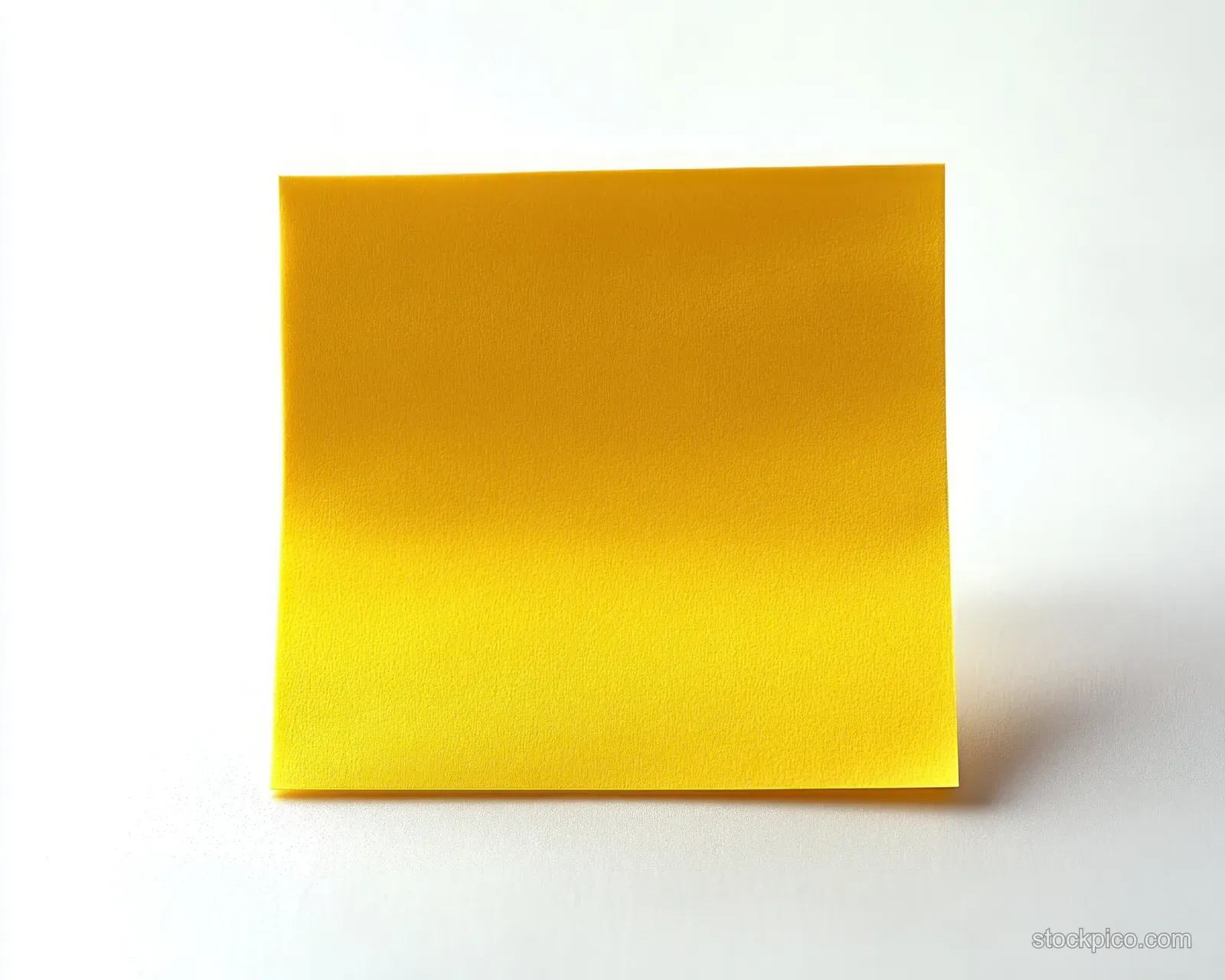 A yellow sticky note pad rests on a white surface with a soft shadow and visible paper texture.
