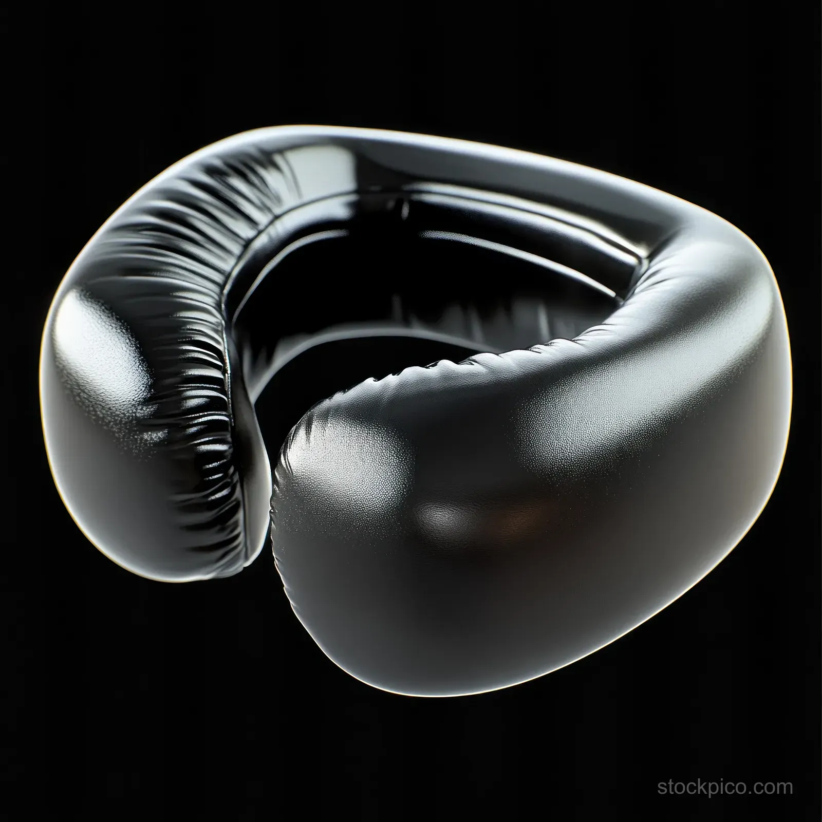 Glossy black boxing headgear floats on a dark background, showing smooth leather and padded protective contours.