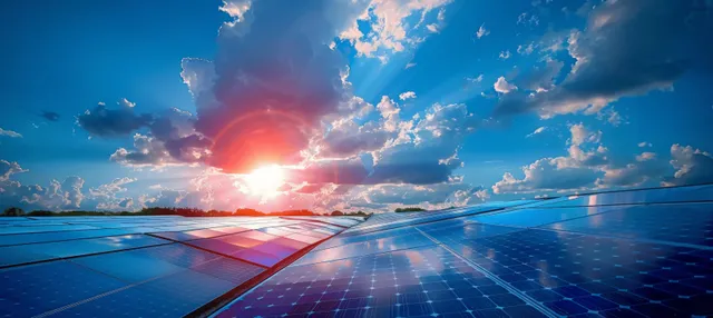 Solar panels in a row under a bright sunrise with dramatic clouds and glowing reflections.