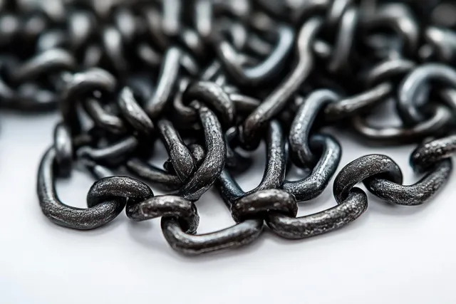 Close-up of intertwined rusty metal chains on a white surface showing oxidized rough chain links.