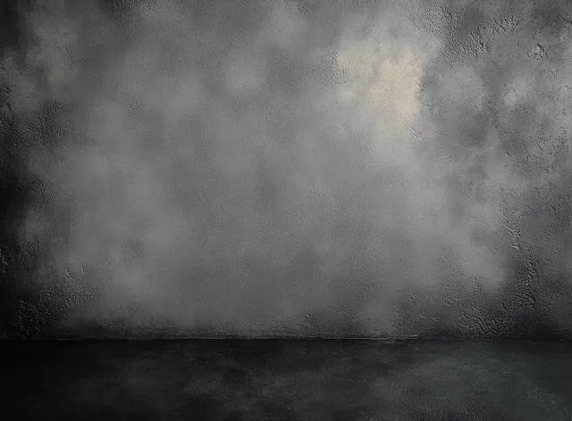 Empty dark concrete wall and floor with rough grunge texture and soft shadowed lighting.