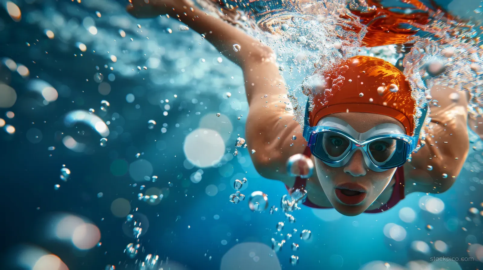 An Australian female swimmer drives forward through clear pool water with splashes and bubbles around her.