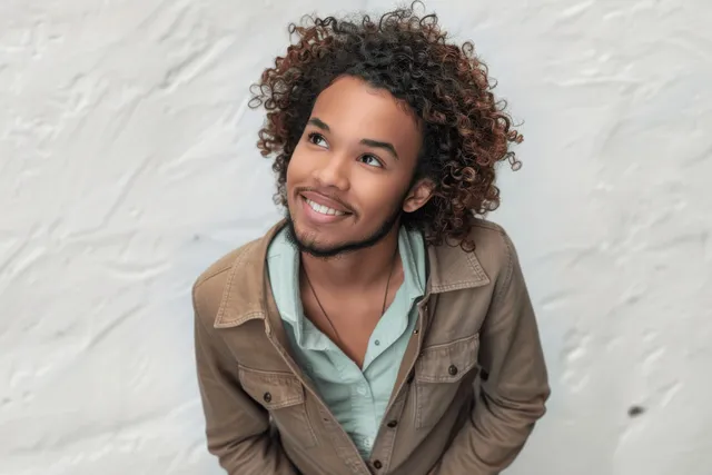 Young man smiling while holding a smartphone outdoors on a city street