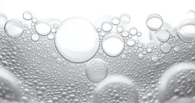 Transparent bubbles of different sizes float in clear liquid with reflective highlights on a bright background.
