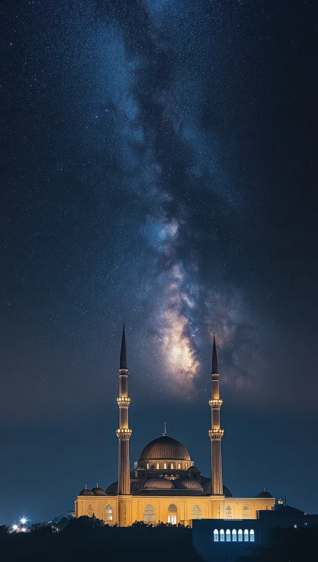 An illuminated mosque with tall minarets beneath the Milky Way glowing over a star-filled night sky.