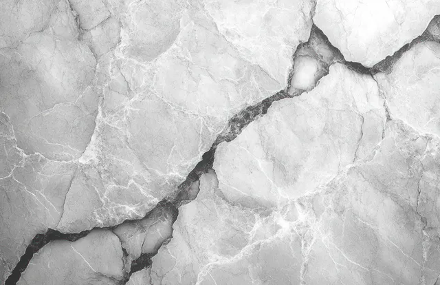 Close-up of white marble slab showing dark veins and jagged cracks