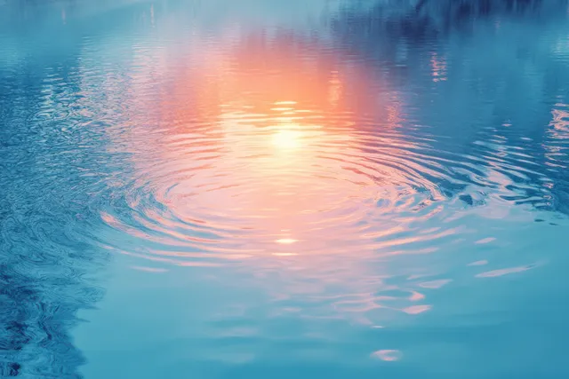 Sunlight reflection creates a circular glow on rippling blue water with soft prismatic color bands.
