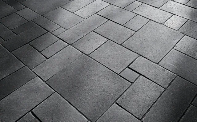 Grey stone pavement close-up with rectangular and square tiles forming a repeating geometric pattern.