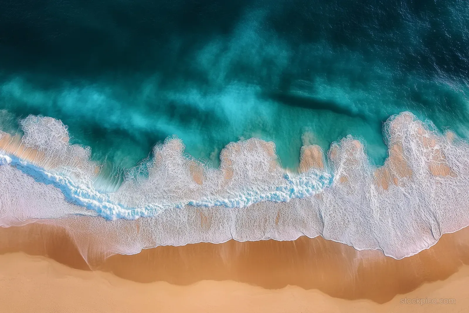 Aerial view of turquoise ocean waves breaking over golden sand, creating foam patterns in a serene summer coastal scene.