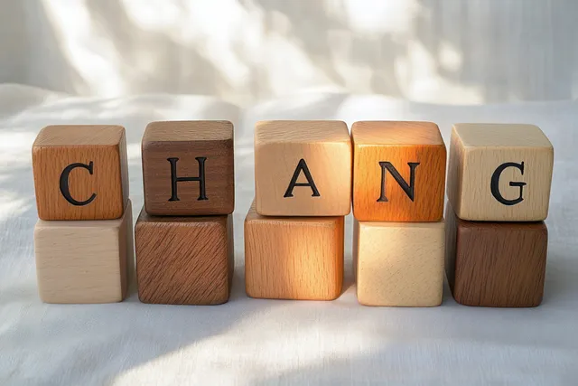 Wooden blocks spelling CHANGING on soft fabric background with warm light