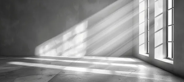 Sunlit shadow stripes on concrete floor beside tall windows in minimalist interior