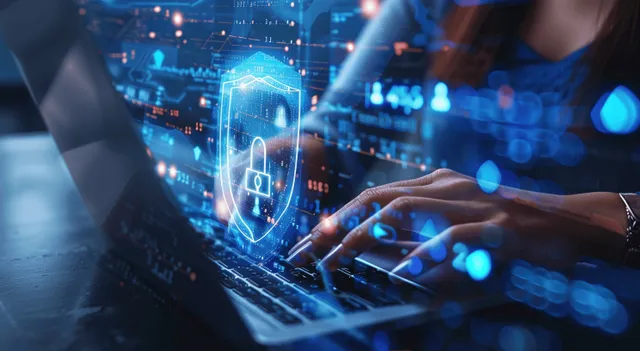 A business woman types on a laptop with glowing shield and padlock overlays protecting network data.