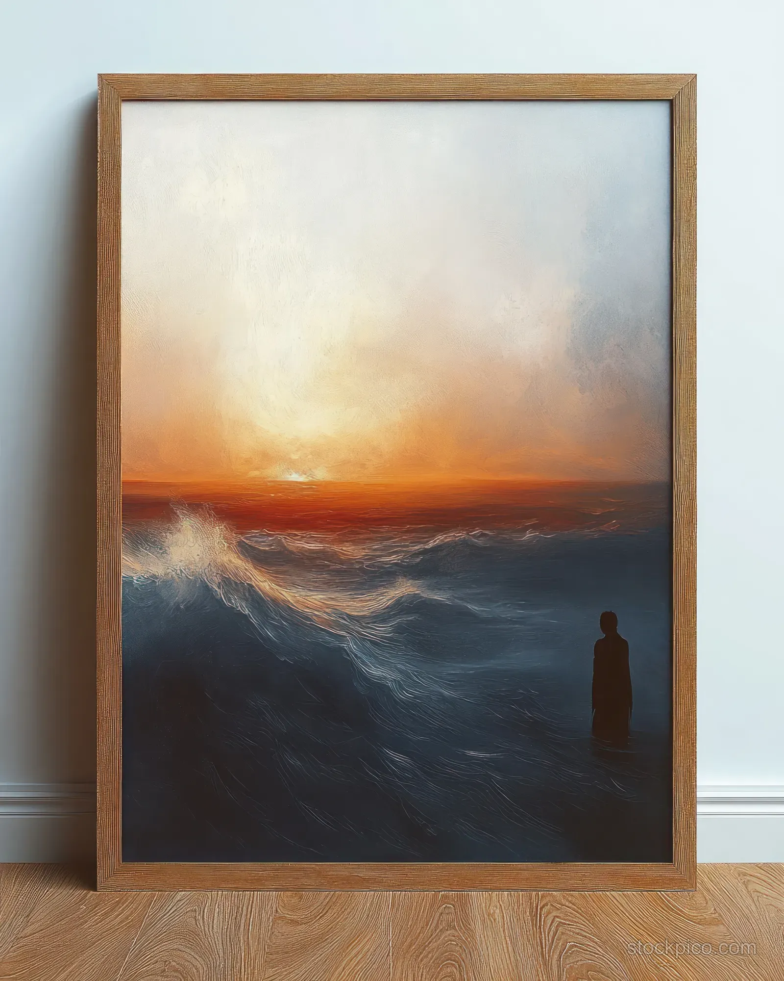 Wooden-framed seascape painting on a wall showing stormy waves at sunset and a lone standing silhouette.