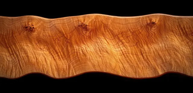 Close-up of polished wooden slab with natural grain and wavy edge on dark background
