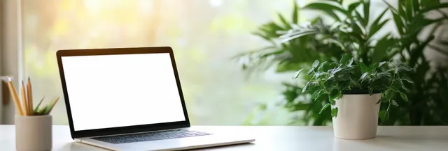Open laptop with a blank white screen on a desk near a window beside green potted plants and pencil holder.