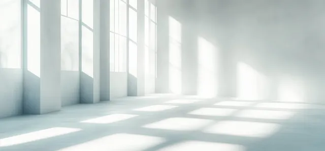 Sunlit empty room with tall window panes casting soft rectangular shadow bands on a smooth floor.