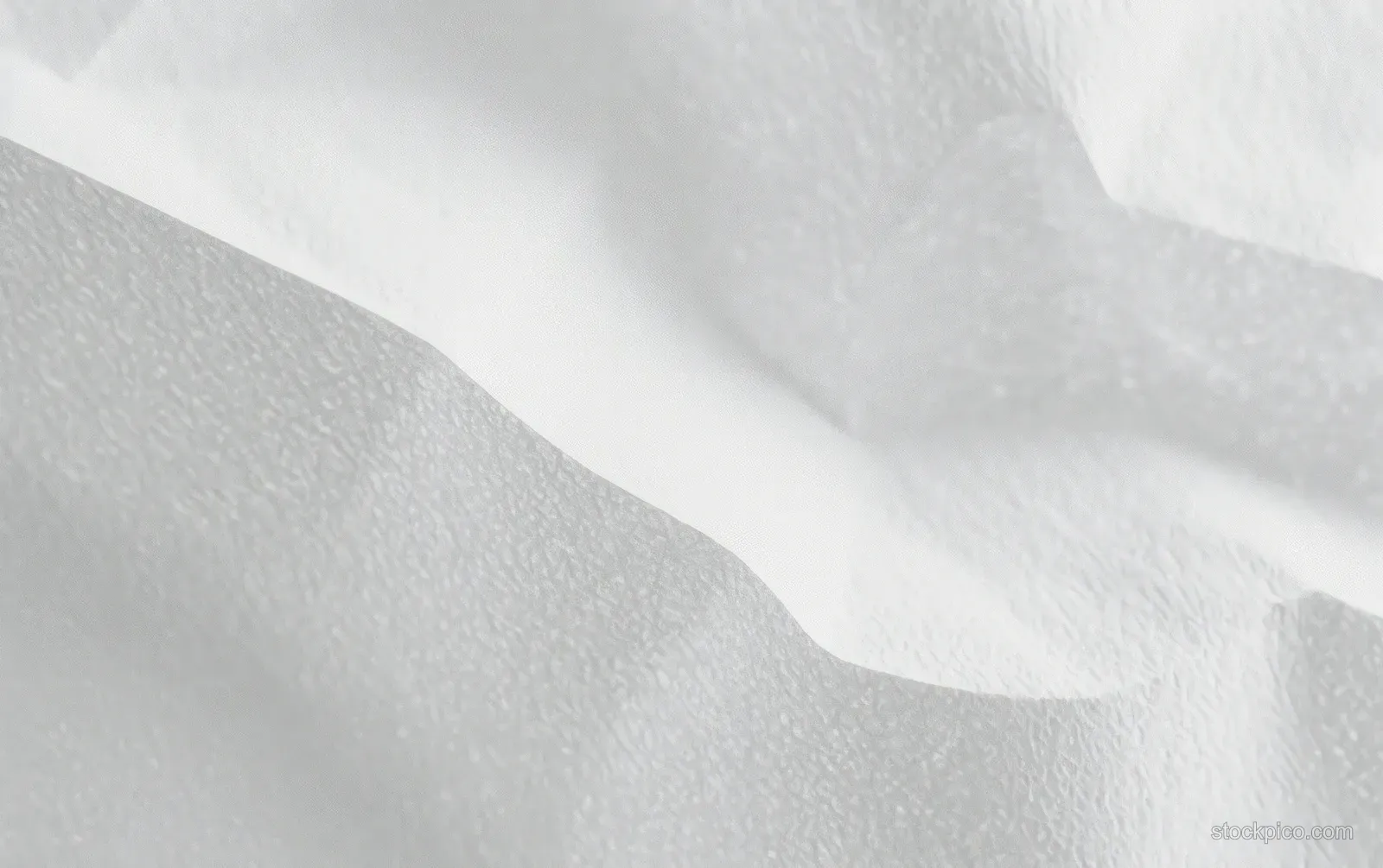 Crumpled white fabric close-up with soft folds and subtle shadow gradients across the surface.