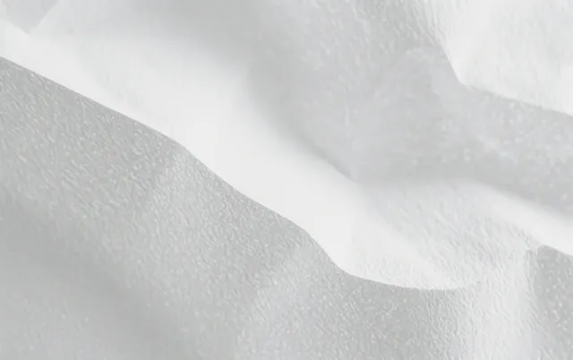 Crumpled white fabric close-up with soft folds and subtle shadow gradients across the surface.
