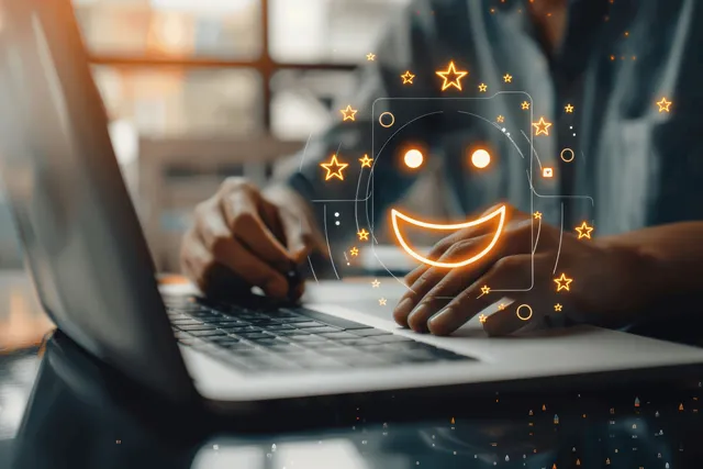 Hands typing on a laptop with a glowing smiling star feedback icon over the screen.