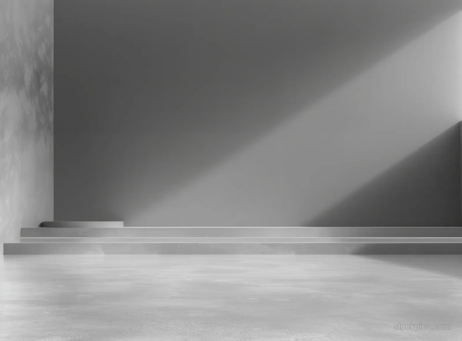 Minimalist empty concrete room interior with a stepped platform illuminated by soft natural light and visible wall shadows.