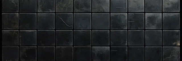 Close-up of a black square tile wall with textured surface, grout grid, and subtle hairline cracks.